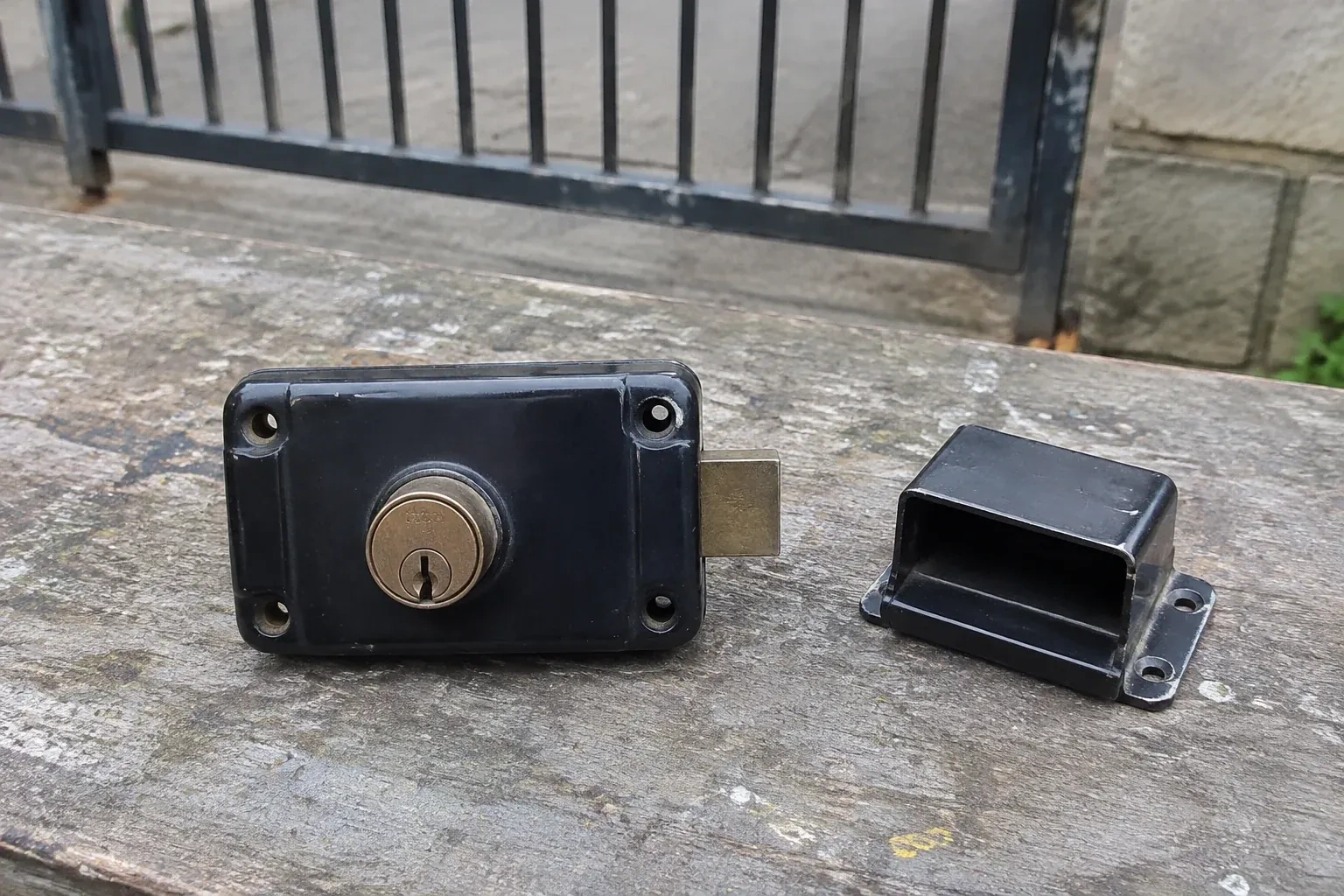 Detached rim gate lock and separate box keeper on an outdoor workbench. — Gate & Building Entry Locks, Woodstock