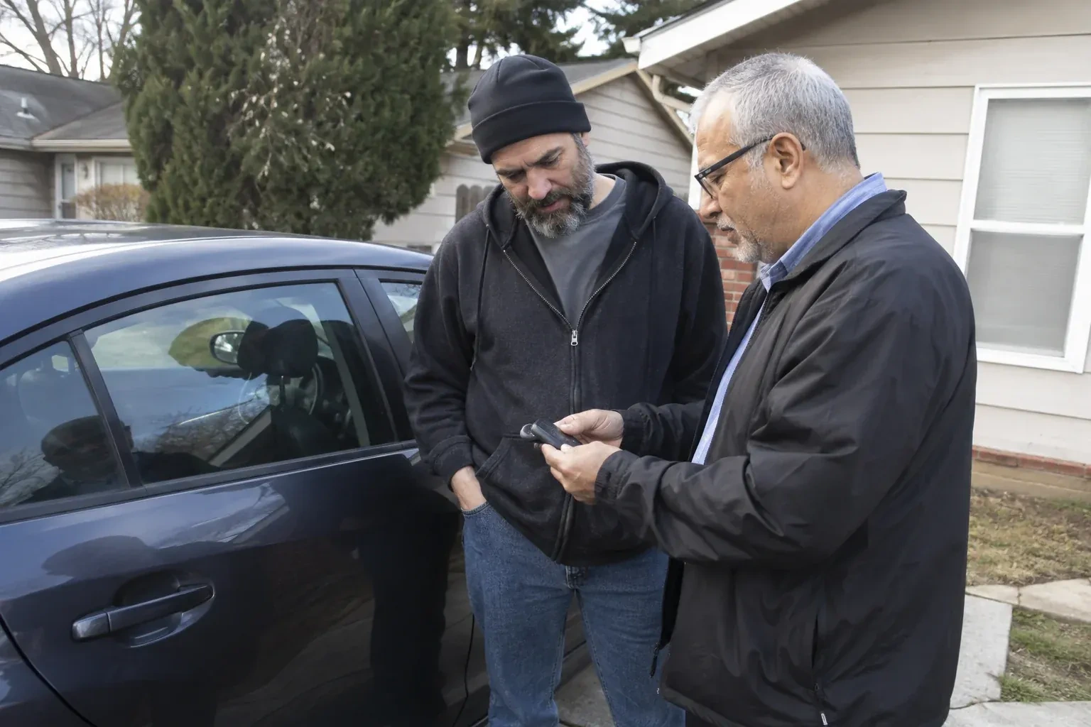 Two adults discussing a key fob beside a parked car. — Car Lockout Service, Woodstock